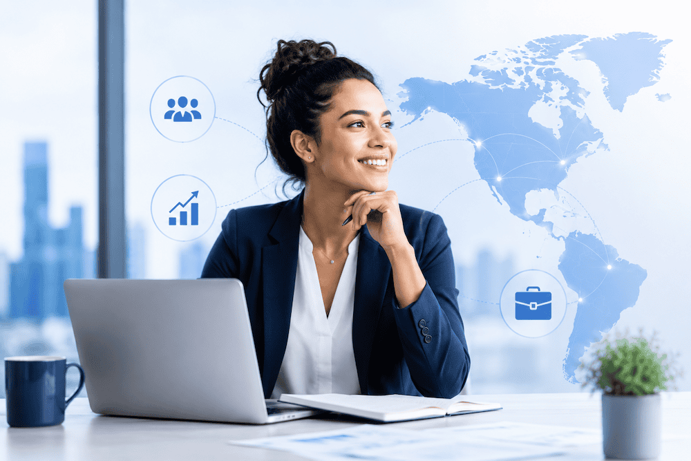 Businesswoman sitting at a desk with a laptop, notebook, and coffee cup, smiling and looking to the side. Background shows a world map and business icons, suggesting global connections and growth.